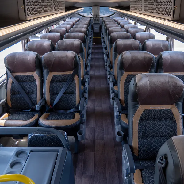 Corredor do piso superior do ônibus, com fileiras de poltronas em couro marrom e tecido azul